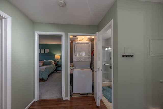 corridor featuring stacked washer / drying machine, wood finished floors, and electric panel