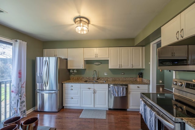 kitchen featuring dark wood finished floors, appliances with stainless steel finishes, white cabinetry, and a sink