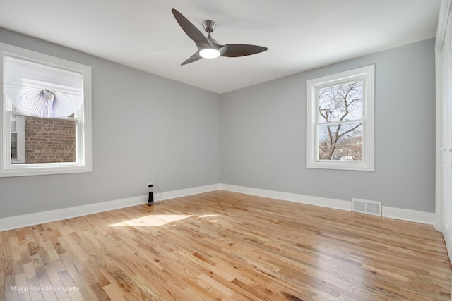 empty room with visible vents, light wood-style flooring, ceiling fan, and baseboards