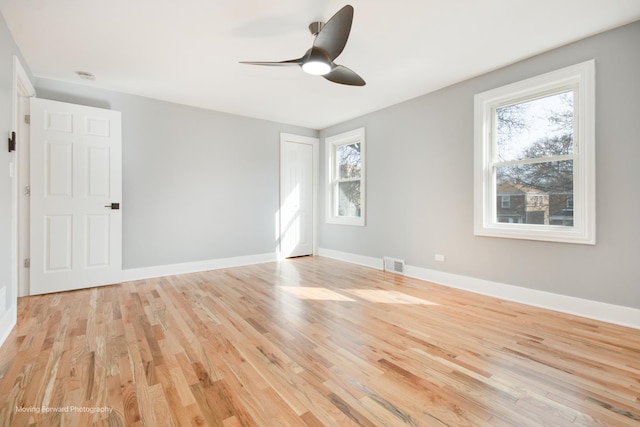 unfurnished room featuring light wood-style floors, a ceiling fan, visible vents, and plenty of natural light