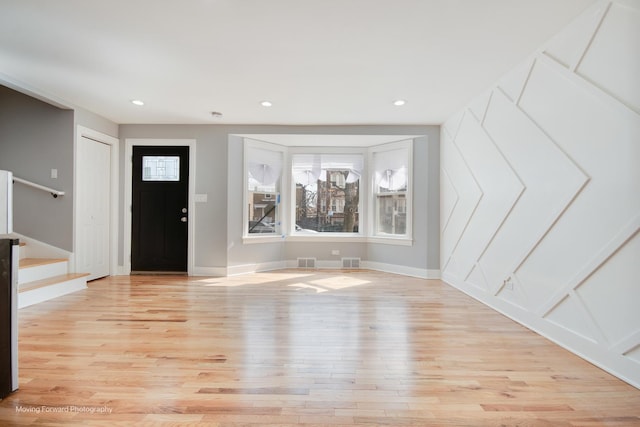 foyer entrance with visible vents, light wood-style flooring, stairway, and baseboards