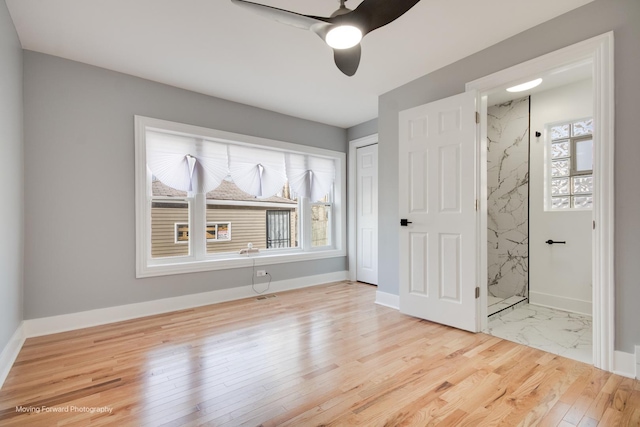 unfurnished bedroom featuring a closet, baseboards, ceiling fan, connected bathroom, and wood finished floors