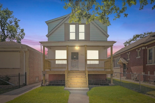 view of front of home with a porch, fence, and a front lawn
