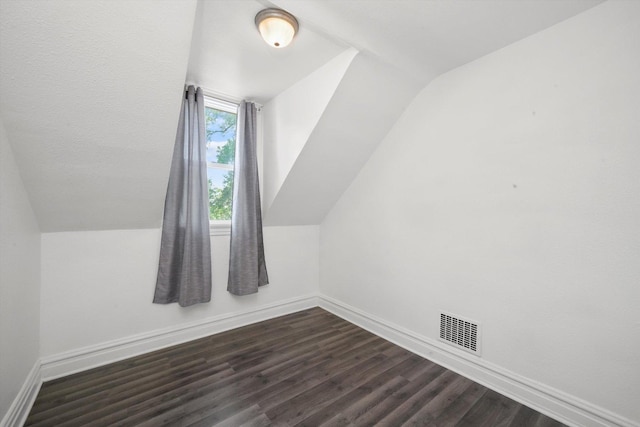 additional living space with dark wood-style flooring, visible vents, baseboards, and vaulted ceiling