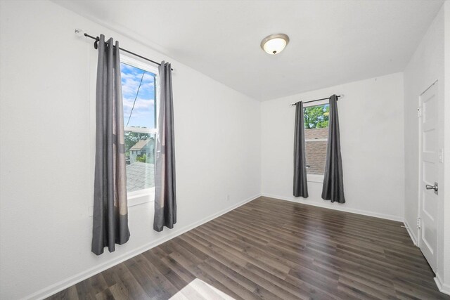 empty room featuring dark wood-style flooring and baseboards