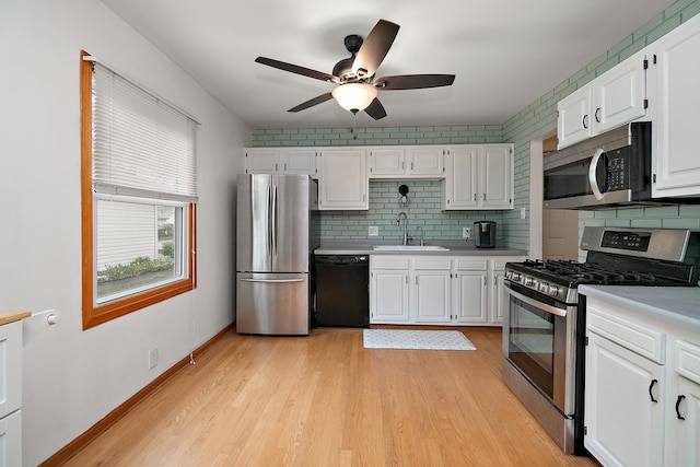 kitchen with a sink, light countertops, stainless steel appliances, a ceiling fan, and backsplash