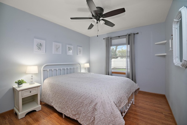 bedroom with a ceiling fan, baseboards, and wood finished floors