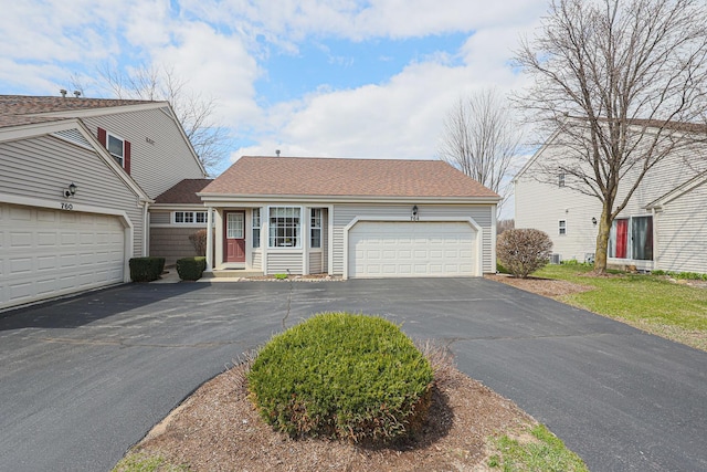 view of front facade featuring an attached garage, driveway, and a shingled roof