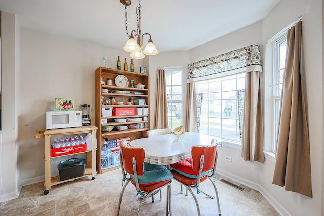 dining space with visible vents, baseboards, an inviting chandelier, and a healthy amount of sunlight
