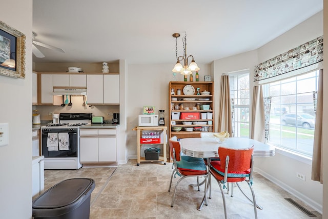 dining space with visible vents, ceiling fan with notable chandelier, baseboards, and a healthy amount of sunlight