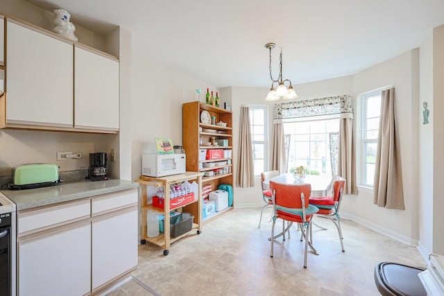 dining room featuring plenty of natural light, baseboards, and an inviting chandelier
