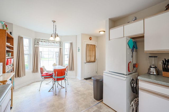 kitchen featuring white cabinets, pendant lighting, baseboards, and light countertops
