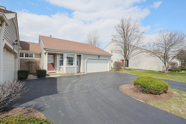 view of front facade featuring an attached garage, a shingled roof, and driveway