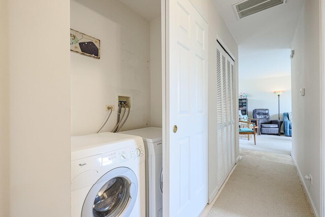 clothes washing area with visible vents, washer and clothes dryer, laundry area, and light carpet