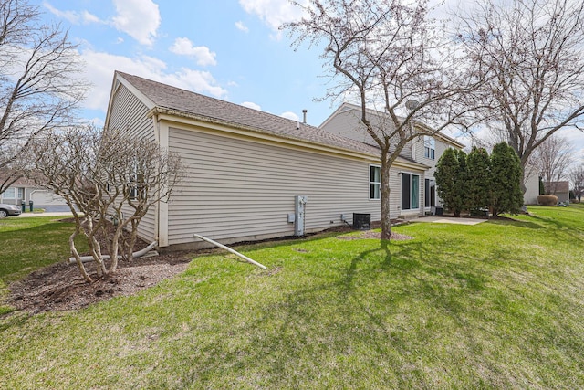 back of house featuring central air condition unit, roof with shingles, and a lawn