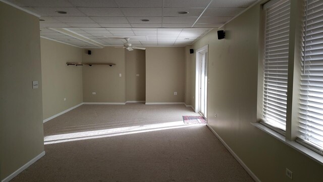 spare room featuring baseboards, a paneled ceiling, light colored carpet, and ceiling fan