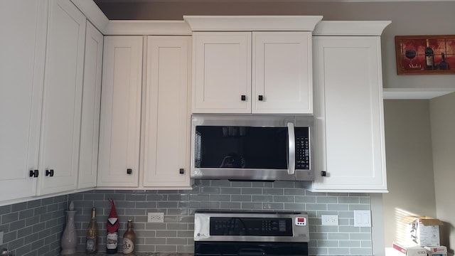 kitchen with stainless steel microwave, tasteful backsplash, and white cabinets