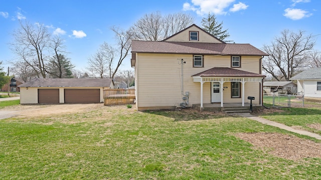 view of front of house with an outbuilding, a detached garage, a porch, a front yard, and fence