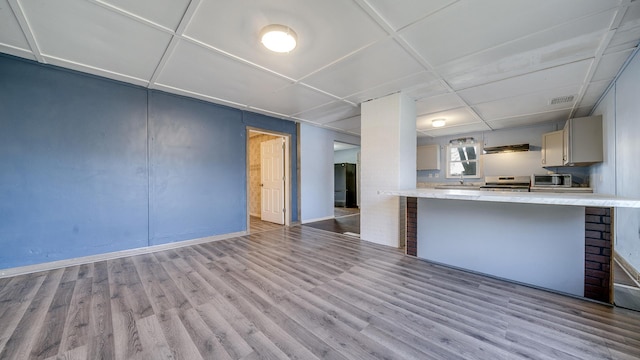 kitchen with a kitchen breakfast bar, baseboards, visible vents, appliances with stainless steel finishes, and wood finished floors
