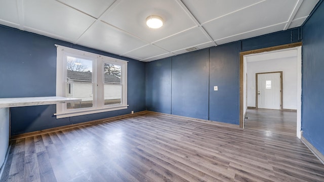 unfurnished room with baseboards, wood finished floors, and a healthy amount of sunlight