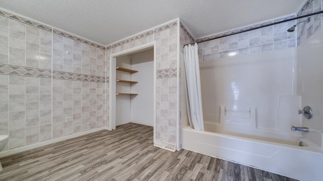 full bath with toilet, tile walls, shower / tub combo with curtain, a textured ceiling, and wood finished floors