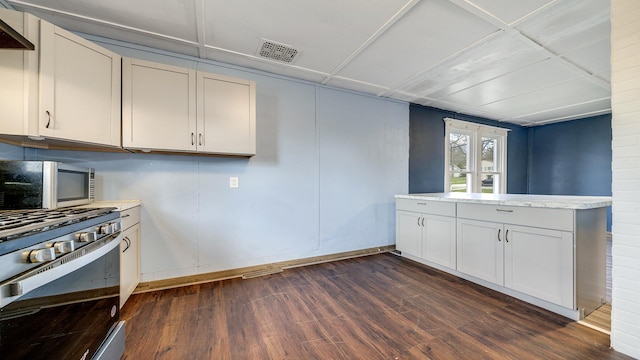 kitchen with appliances with stainless steel finishes, dark wood-style flooring, light countertops, and visible vents