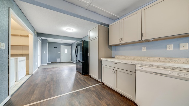 kitchen featuring freestanding refrigerator, dark wood-type flooring, washing machine and clothes dryer, light countertops, and white dishwasher
