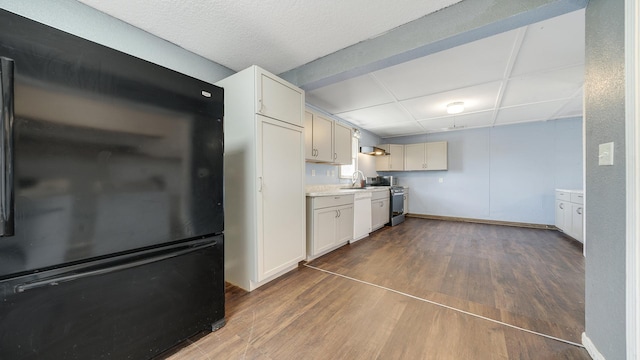 kitchen featuring baseboards, light countertops, freestanding refrigerator, dark wood-type flooring, and dishwasher