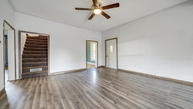 unfurnished living room with visible vents, a ceiling fan, a textured ceiling, wood finished floors, and stairs