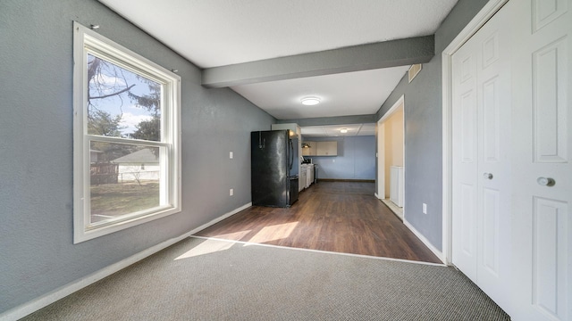 corridor featuring carpet, baseboards, and beamed ceiling