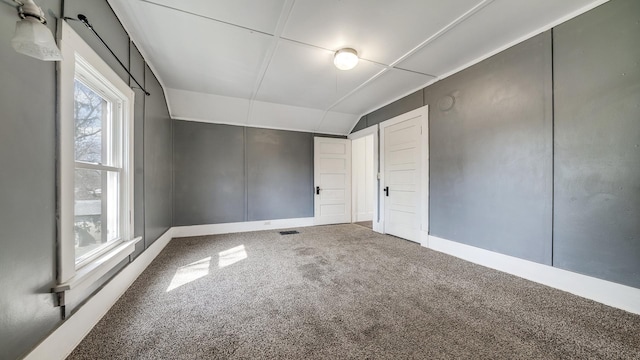 interior space featuring carpet floors, baseboards, vaulted ceiling, and visible vents