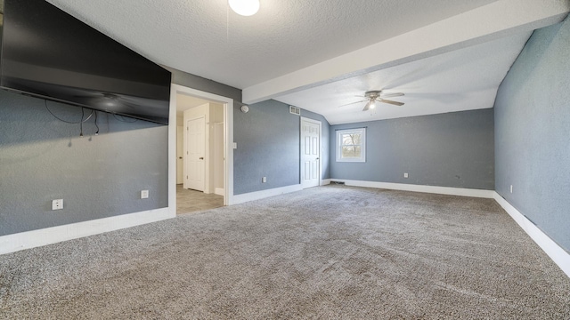 unfurnished bedroom with a closet, carpet, a textured wall, a textured ceiling, and beam ceiling