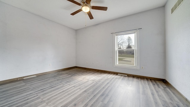 empty room with wood finished floors, ceiling fan, and visible vents