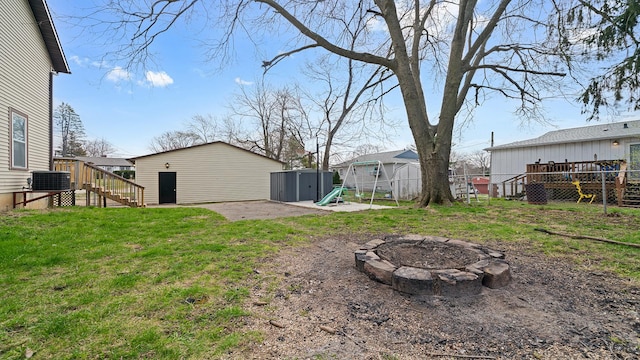 view of yard featuring a storage shed, an outdoor fire pit, fence, stairs, and an outbuilding