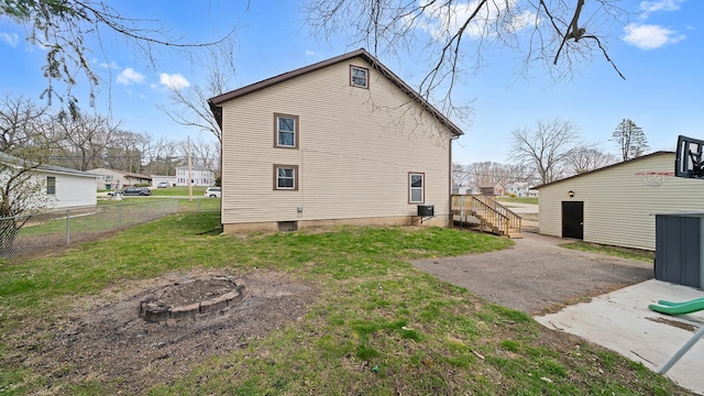 rear view of house featuring a fire pit, a yard, and fence