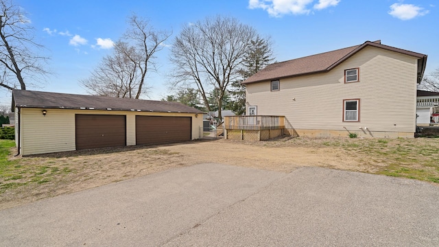 view of side of home with a deck, an outbuilding, and a detached garage
