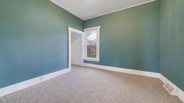 carpeted empty room with ornamental molding, visible vents, and baseboards