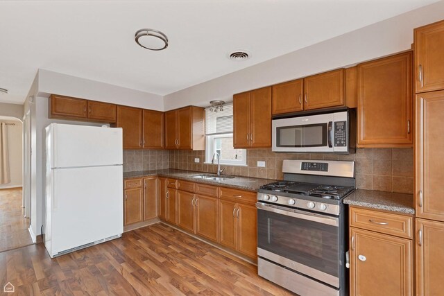 5753 S Moody Ave, Chicago, IL 60638 - kitchen with visible vents, a sink, brown cabinets, wood finished floors, and stainless steel appliances