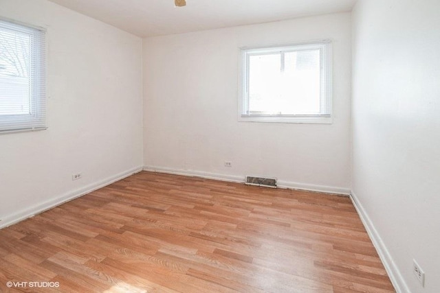spare room featuring light wood finished floors, baseboards, and visible vents