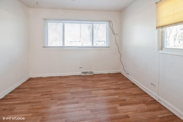 empty room with light wood finished floors, visible vents, and plenty of natural light