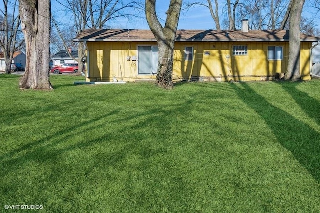 back of property featuring a chimney and a lawn