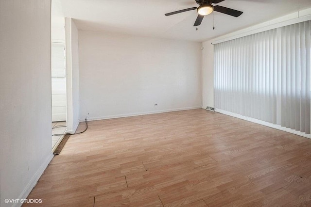 spare room featuring wood finished floors, ceiling fan, baseboards, and visible vents