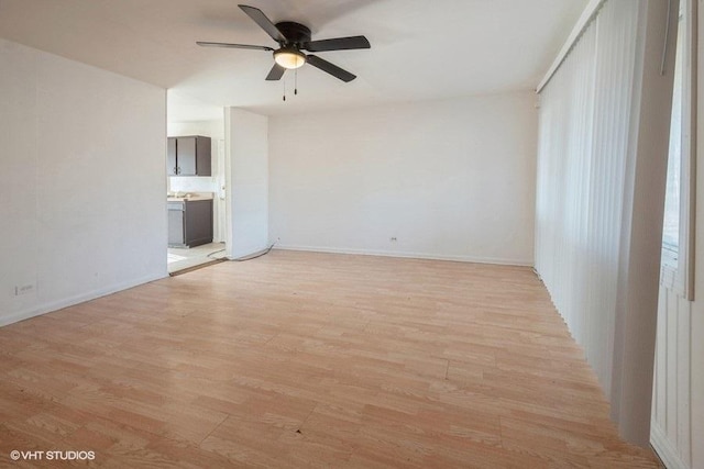 spare room featuring light wood-type flooring, baseboards, and a ceiling fan
