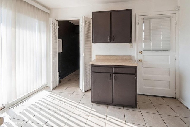 kitchen with light tile patterned floors, visible vents, light countertops, and dark brown cabinets