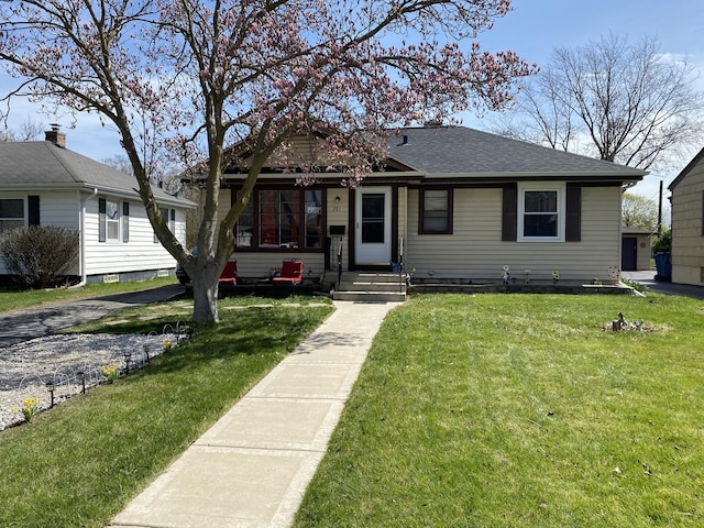 bungalow with a shingled roof and a front lawn