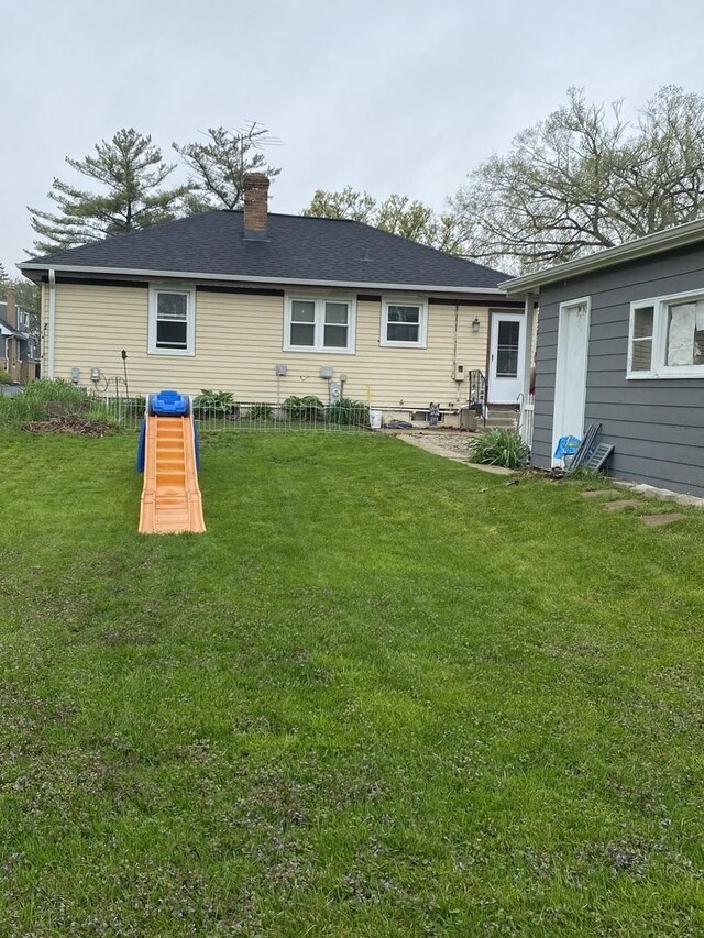 rear view of property featuring entry steps, a chimney, and a yard