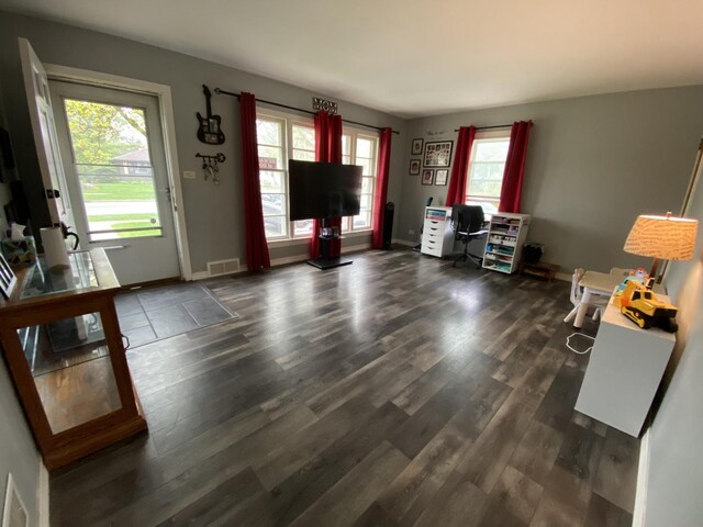 living area with baseboards, visible vents, and dark wood-type flooring