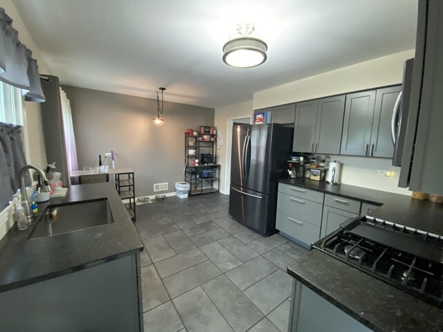 kitchen with hanging light fixtures, a sink, freestanding refrigerator, baseboards, and visible vents