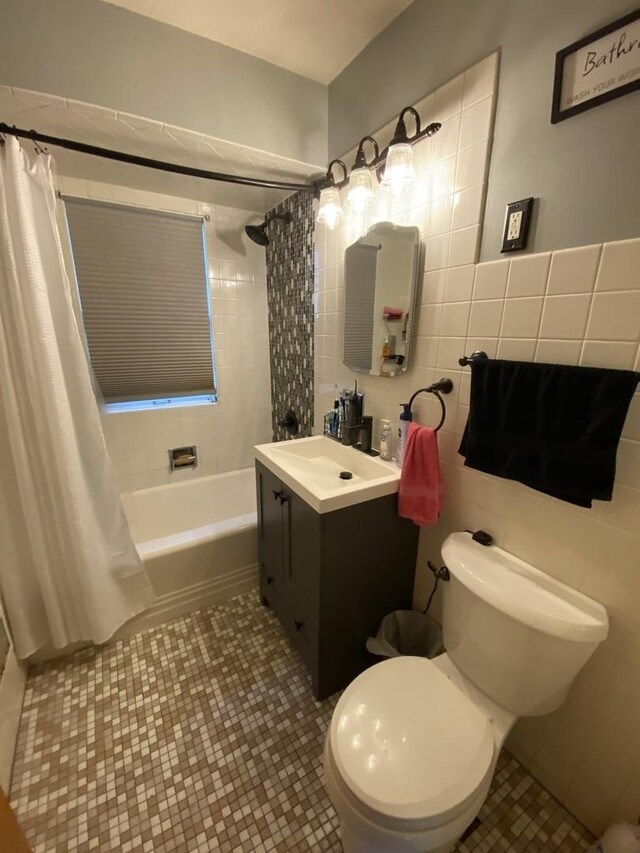 bathroom with vanity, toilet, tile patterned floors, tile walls, and shower / tub combo