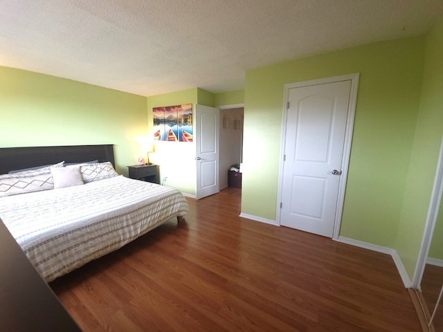 bedroom featuring baseboards, wood finished floors, and a textured ceiling